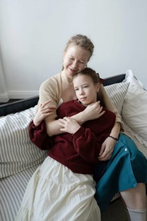 A tender moment of a mother and daughter sharing an embrace while seated on a cozy couch, capturing
