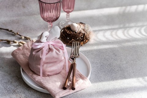 An artistic Easter table arrangement featuring a bunny-themed pink cloth wrap, elegantly tied,