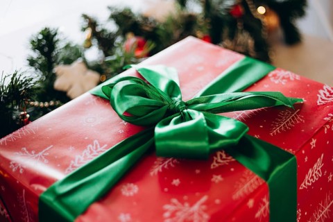 A beautifully wrapped Christmas gift in red paper with white snowflake designs, topped with a