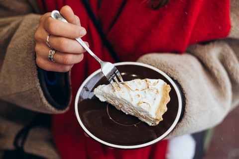 Cropped unrecognizable woman outside wearing winter garments, focusing on her hands as she uses a