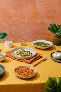 Lavish Italian dinner spread featuring bowls of basil pesto gnocchi, a fresh green salad, sweet