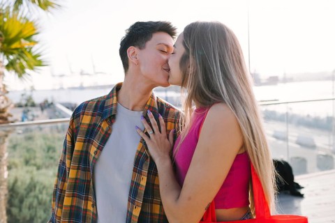 A happy lesbian couple shares a moment of love outdoors while kissing, celebrating diversity and