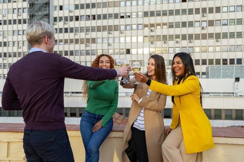 A joyful group of friends celebrating at a rooftop party, clinking glasses and smiling The festive