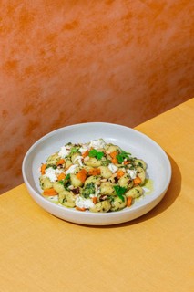 Top view of a savory Italian dish featuring gnocchi with vibrant green pesto, walnuts, parmesan