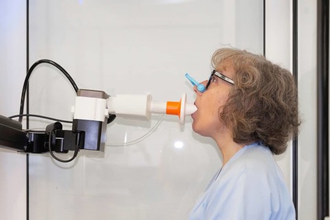 A woman is shown with nose clip performing a spirometry test to assess her lung function in a