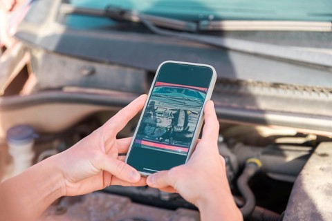 A person uses a smartphone to photograph car damage for insurance documentation The image