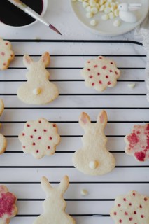 Top view of Easter bunny-shaped cookies delicately painted with hibiscus tea on a cooling rack. The