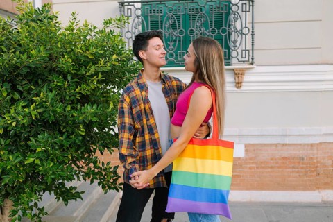 A loving lesbian couple shares a warm embrace while holding hands in an urban setting. One partner