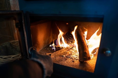 A close-up view of a vibrant fire within a blue wood burning stove, as cropped unrecognizable