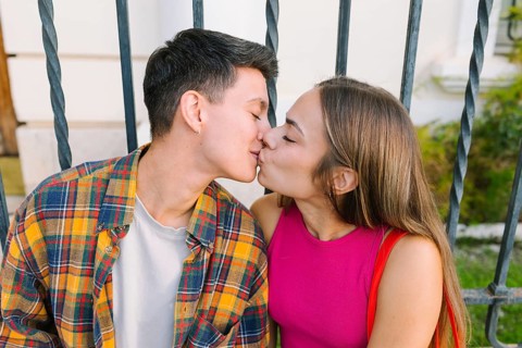 A happy lesbian couple shares a tender kiss while seated together, embracing love and affection.