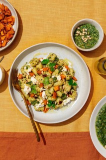Top view of a colorful plate featuring potato gnocchi tossed with green pesto, garnished with