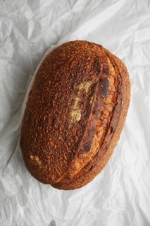 Top view of a freshly baked sourdough bread with a crusty top, resting on crumpled white paper