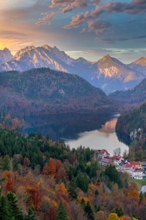 A picturesque view of a village nestled near a serene lake, surrounded by autumn foliage and the