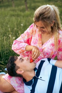 A loving couple shares a sweet moment outdoors as the woman playfully feeds her partner a