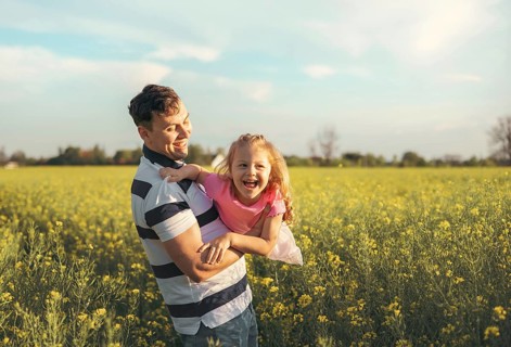 A young father and his little daughter play happily in nature in the summer. Happy parenting and