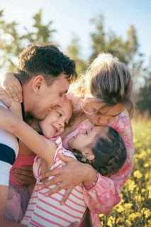 A loving family shares a heartfelt embrace surrounded by golden flowers in the countryside The