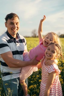 A young father and two daughters have fun together outdoors in the summer. Happy parenting and