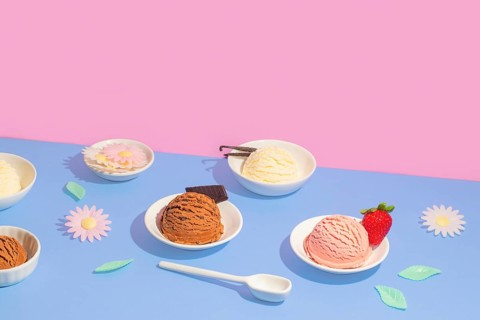 Vibrant image featuring bowls of various ice cream flavors on a dual-tone pink and blue background.