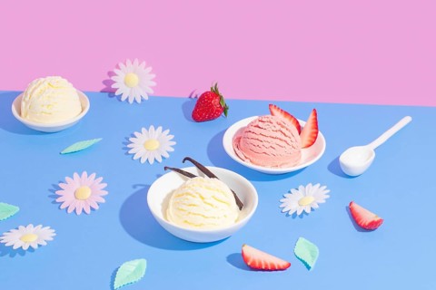 Vibrant split background in pink and blue showcasing various ice cream flavors. The scene includes