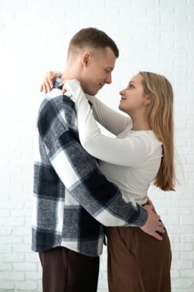 A loving couple shares a warm embrace in a brightly lit room, conveying a sense of happiness and