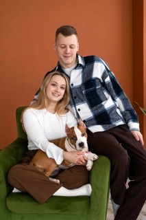 A young Caucasian man and woman smiling, seated comfortably in an armchair with their white and