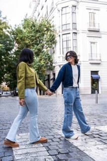 A lesbian couple holding hands while walking on a cobblestone street in the city, surrounded by
