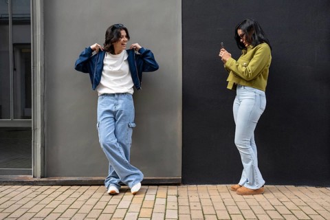 A lesbian couple captures a candid moment outdoors. Both appear happy and relaxed in casual attire
