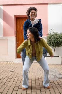 A joyful lesbian couple shares a playful moment outdoors, with one partner giving the other a