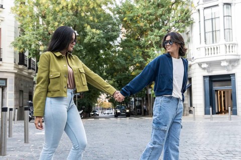 A lesbian couple enjoys a delightful walk hand-in-hand through a picturesque urban setting. They