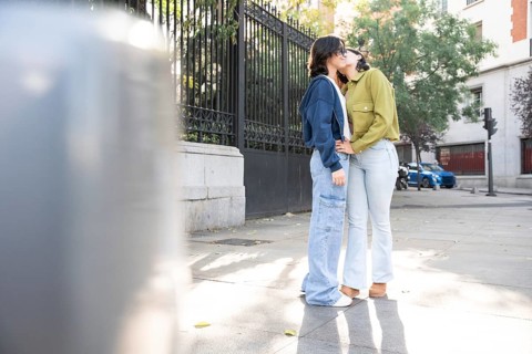 A loving lesbian couple enjoying a sunny day on a city street. They are embracing and sharing a