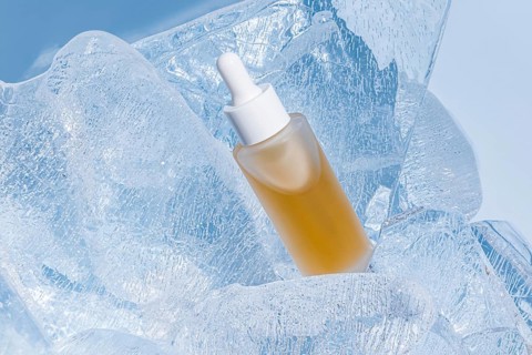 A skincare serum bottle nestled in sparkling clear ice, accentuating the concept of freshness and