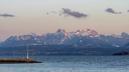 A breathtaking view of the snow-capped Swiss and French Alps seen from the shores of Lake Leman in