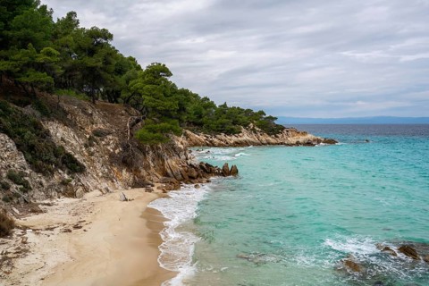 Mega Portokali Beach in southern Greece features a secluded sandy cove with turquoise waters and