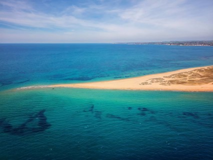 Aerial view of Epanomi Sandbar Beach on the coast of Greece. The golden sand stretches into the