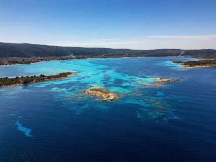 Drone view of Diaporos Island and Karydi Beach in Greece, showcasing crystal-clear turquoise