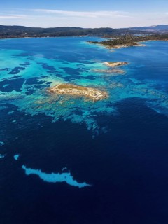 Aerial view of Diaporos Island with vibrant turquoise waters and rocky formations, surrounded by