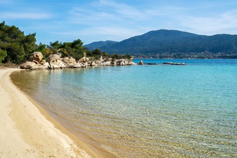 A pristine beach on Diaporos Island in Greece with turquoise waters and golden sand. Surrounded by
