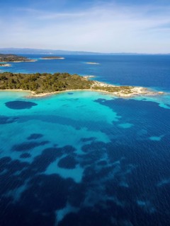 Aerial view of Diaporos Island and Karydi Beach, Greece, with bright turquoise waters, green