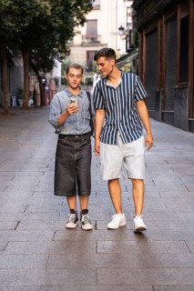 Stylish gay couple walking hand in hand on a quiet street in Madrid, Spain. One checks their