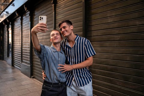 A joyful gay couple taking a selfie on the lively streets of Madrid. They express love and