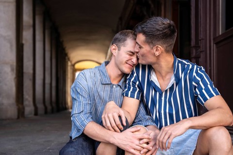A loving gay couple shares an affectionate moment on the picturesque streets of Madrid. Their
