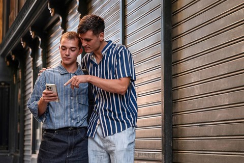 Stylish young gay couple standing together on a city street in Madrid, Spain, sharing a moment