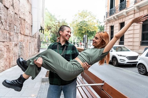Joyful Colombian lesbian couple sharing a playful moment in the city. Celebrate love, diversity,