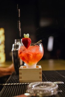 A professional bartender skillfully prepares a vibrant cocktail at a chic bar. The drink is