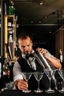 A skilled bartender expertly prepares cocktails in a stylish bar setting, showcasing mixology