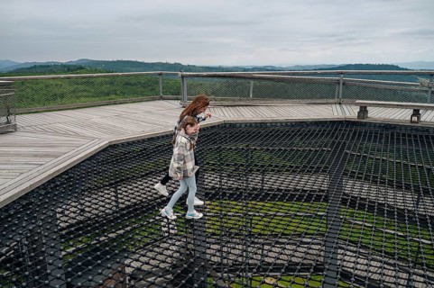 Cheerful woman and her child traversing the treetop walk at Bachledka in Slovakia