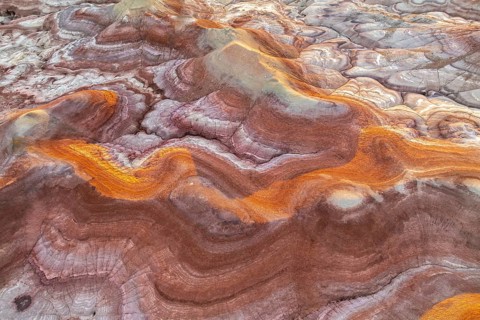Capture of Utah's bentonite formations, showcasing swirling patterns and vibrant hues of gold and