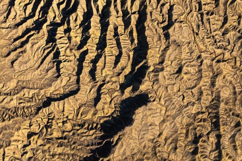 Aerial photograph showcasing intricate golden desert textures at Caineville Mesa, Utah. The
