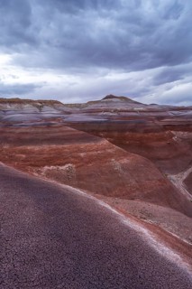 The vibrant, layered Hanksville Bentonites in Utah's desert landscape stretch under dramatic,