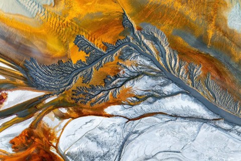 Explore intricate fractal mud textures with vivid earthy tones. This aerial view showcases stunning